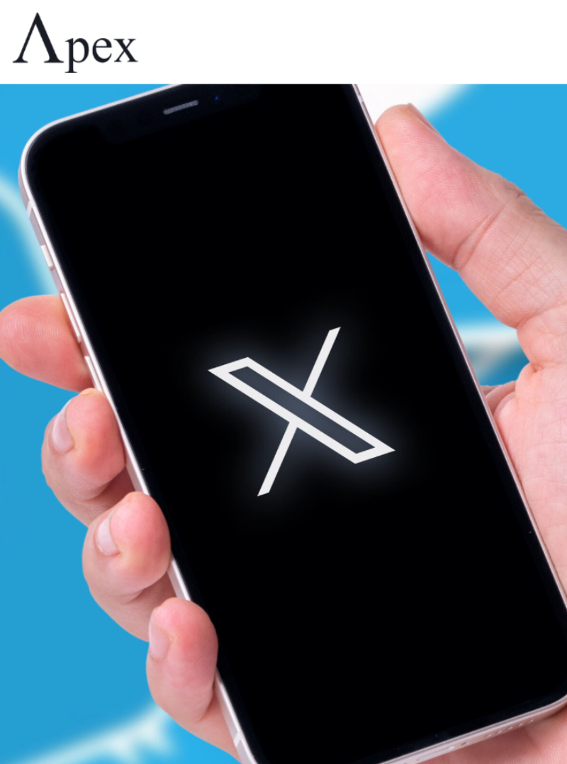 Hand holding a smartphone displaying the X logo on a black screen
