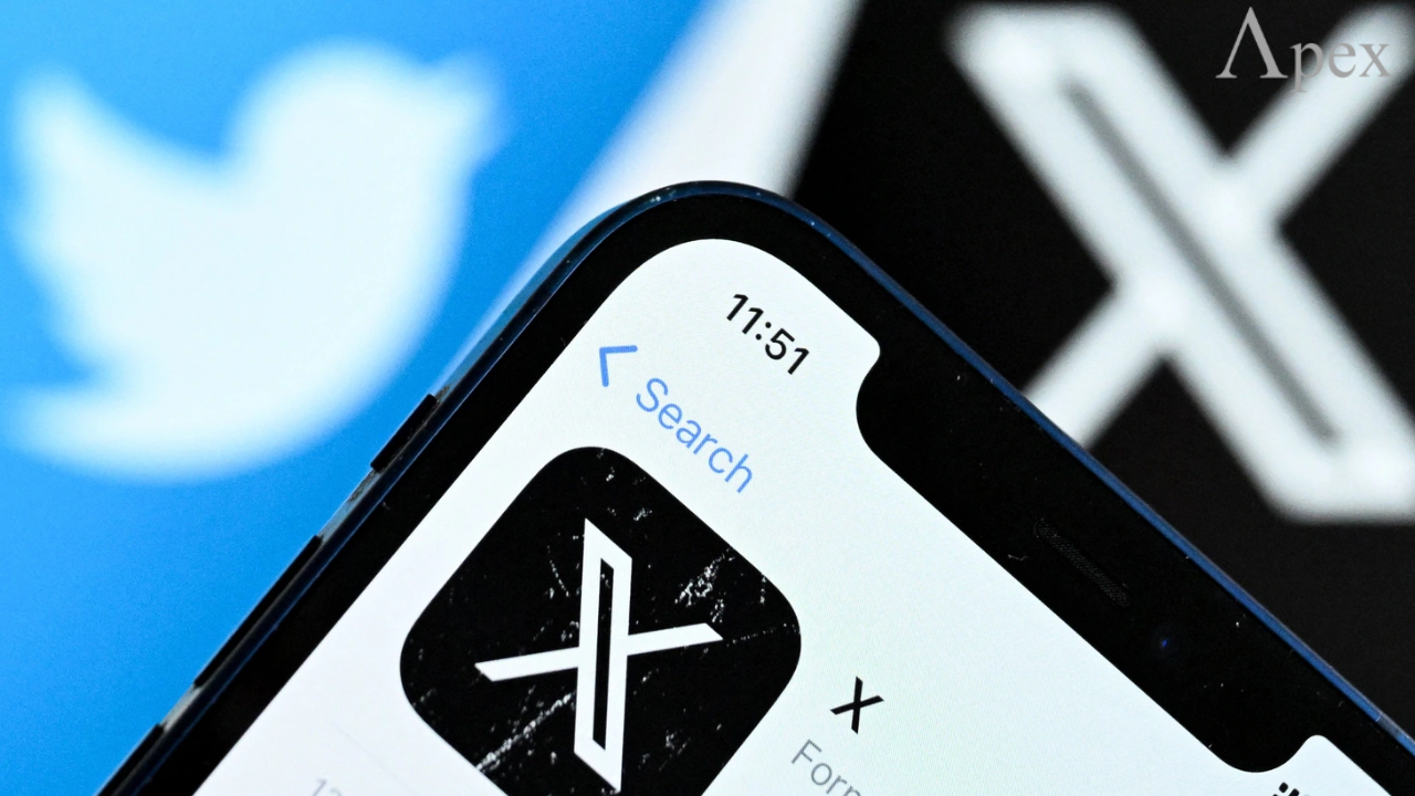 Close-up of a smartphone showing the X app icon in the store, with the old Twitter bird logo blurred in the background.